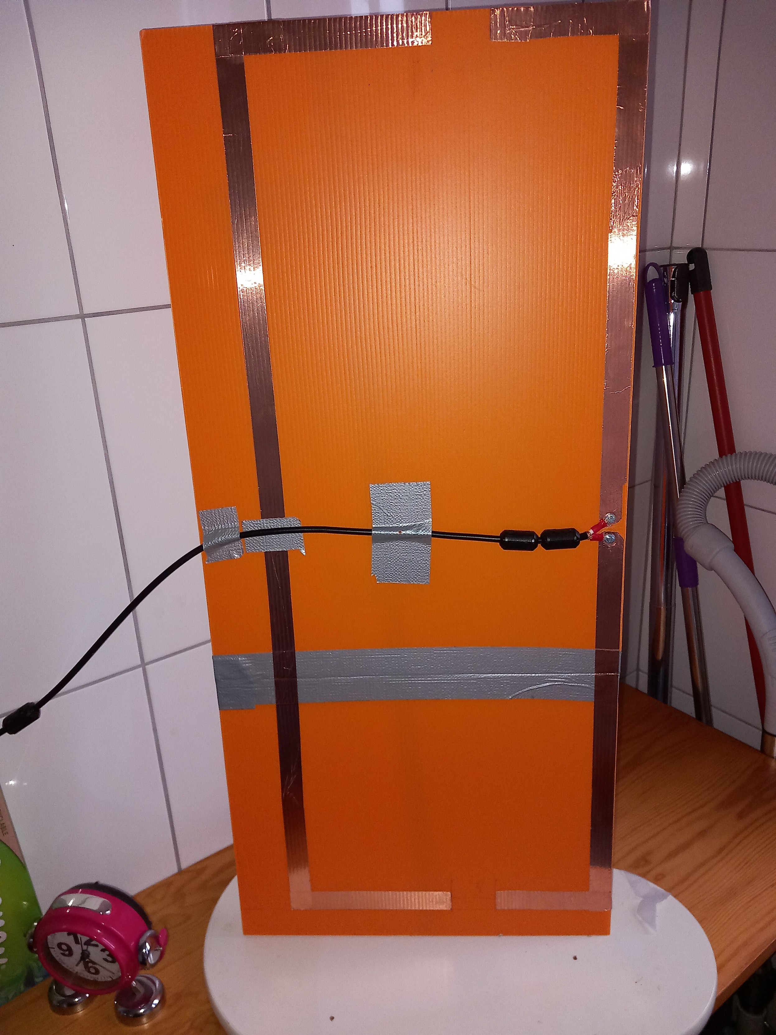 Moxon antenna made of copper tape on an orange plastic board. Other pieces of tapes keep the coaxial straight.